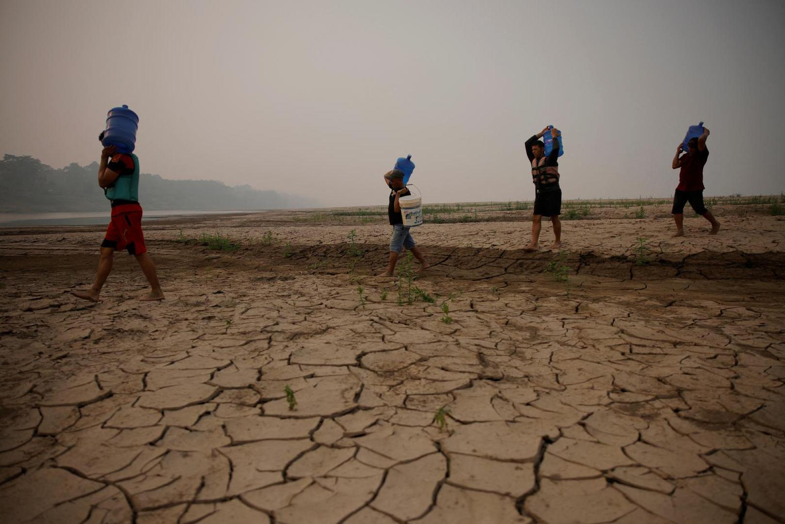 River dwellers carry water gallons, on the sandbanks of the Madeira river, to bring to the isolated region of Paraizinho community, during the worst drought of the river in history, Humaita, Amazonas state, Brazil September 8, 2024. REUTERS/Bruno Kelly Photo: BRUNO KELLY/REUTERS