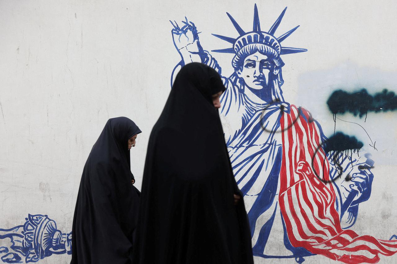 Women walk past an anti-U.S. mural on a street in Tehran