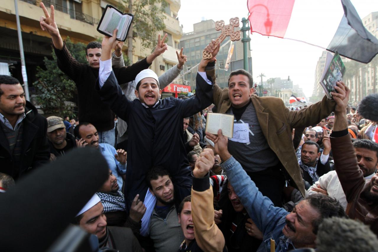 \'Egyptian Coptic Christians and Muslims raise a Cross and a Koran, Islam\'s holy book, at Cairo\'s Tahrir Square on February 6, 2011 on the 13th day of protests calling for ouster of President Hosni 