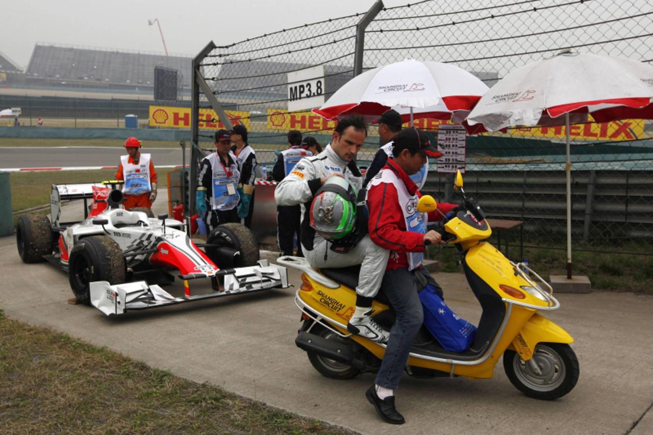 'HRT Formula One driver Vitantonio Liuzzi of Italy gets a lift on a scooter after hitting a barrier during the first practice session at the Chinese F1 Grand Prix at Shanghai International Circuit Apr