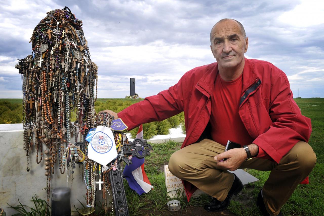 'TO GO WITH AFP STORY BY KATARINA SUBASIC Croatian war veteran Davor Markobasic poses in front of the Ovcara mass grave monument made of hundreds of rosaries, near the eastern Croatian town of Vukovar