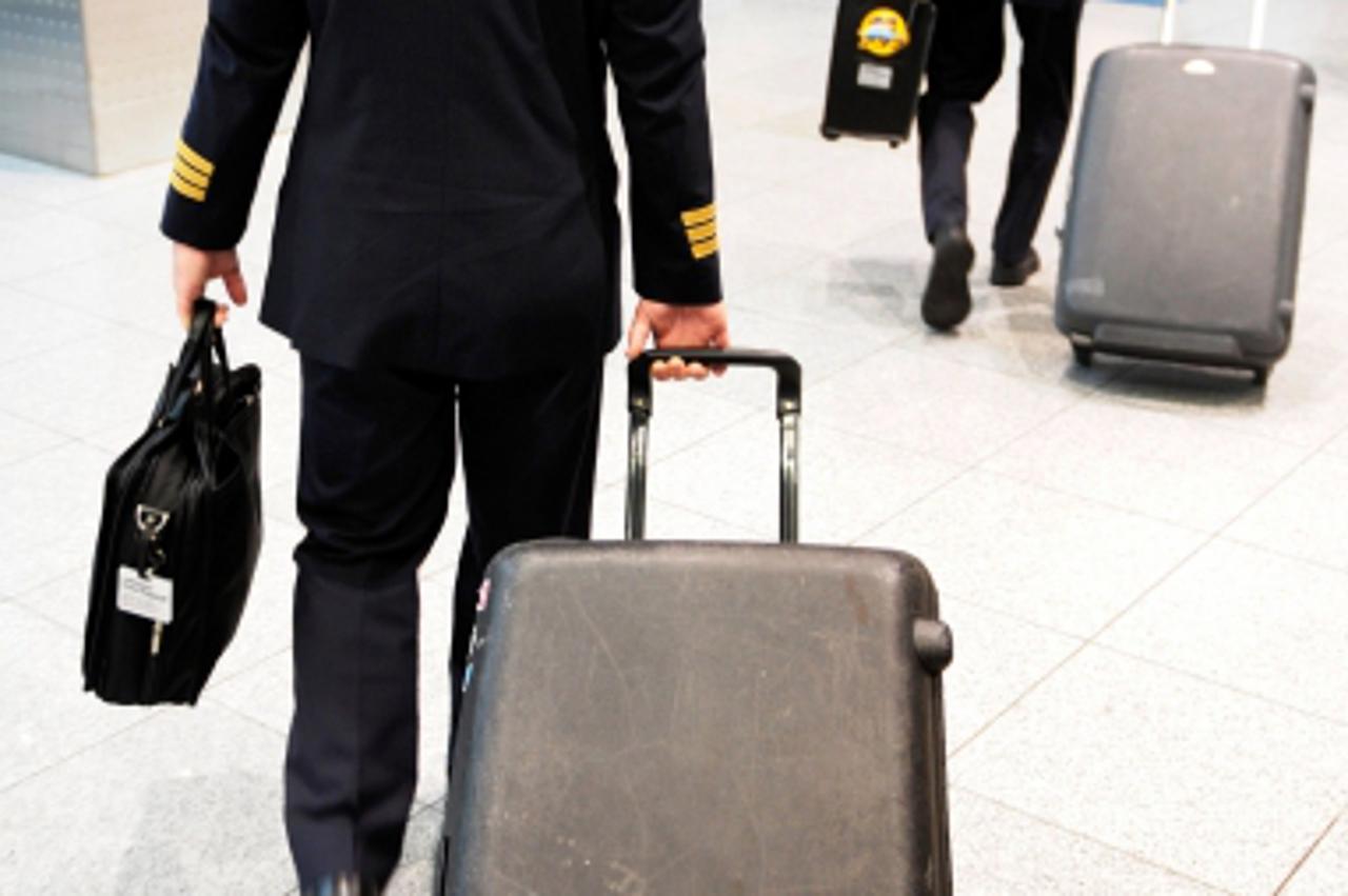 \'Pilots walk through the departure terminal at Duesseldorf\'s Airport on July 7, 2008. The leading German airline, Lufthansa, said it had cancelled more than 200 domestic and European flights schedul