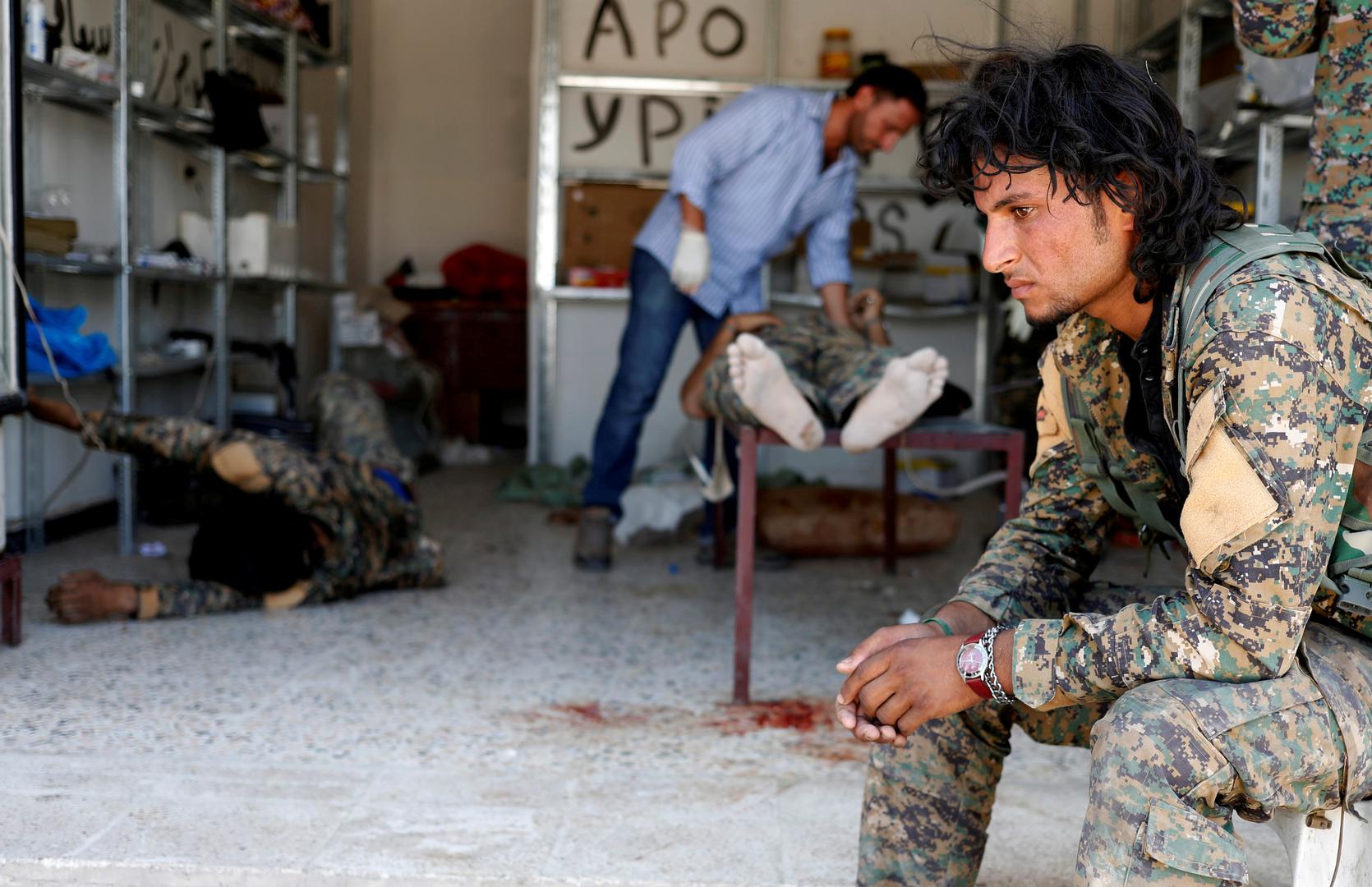 Borac Sirijskih demokratskih snaga sjedi dok medicinsko osoblje brine o suborcu kojeg su ranili iz snajpera pripadnici Islamske države u Rakki.