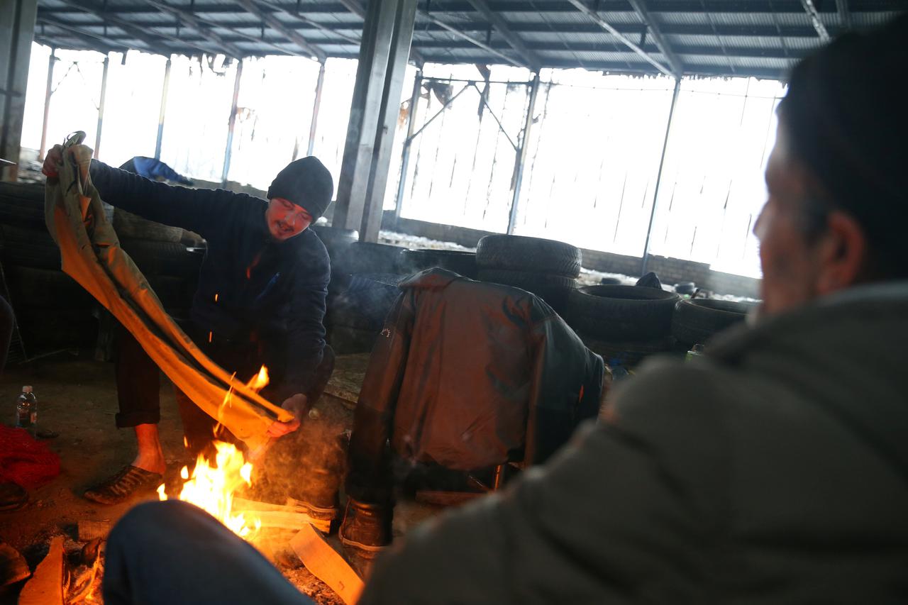 Migrants warm up in an abandoned factory near Velika Kladusa