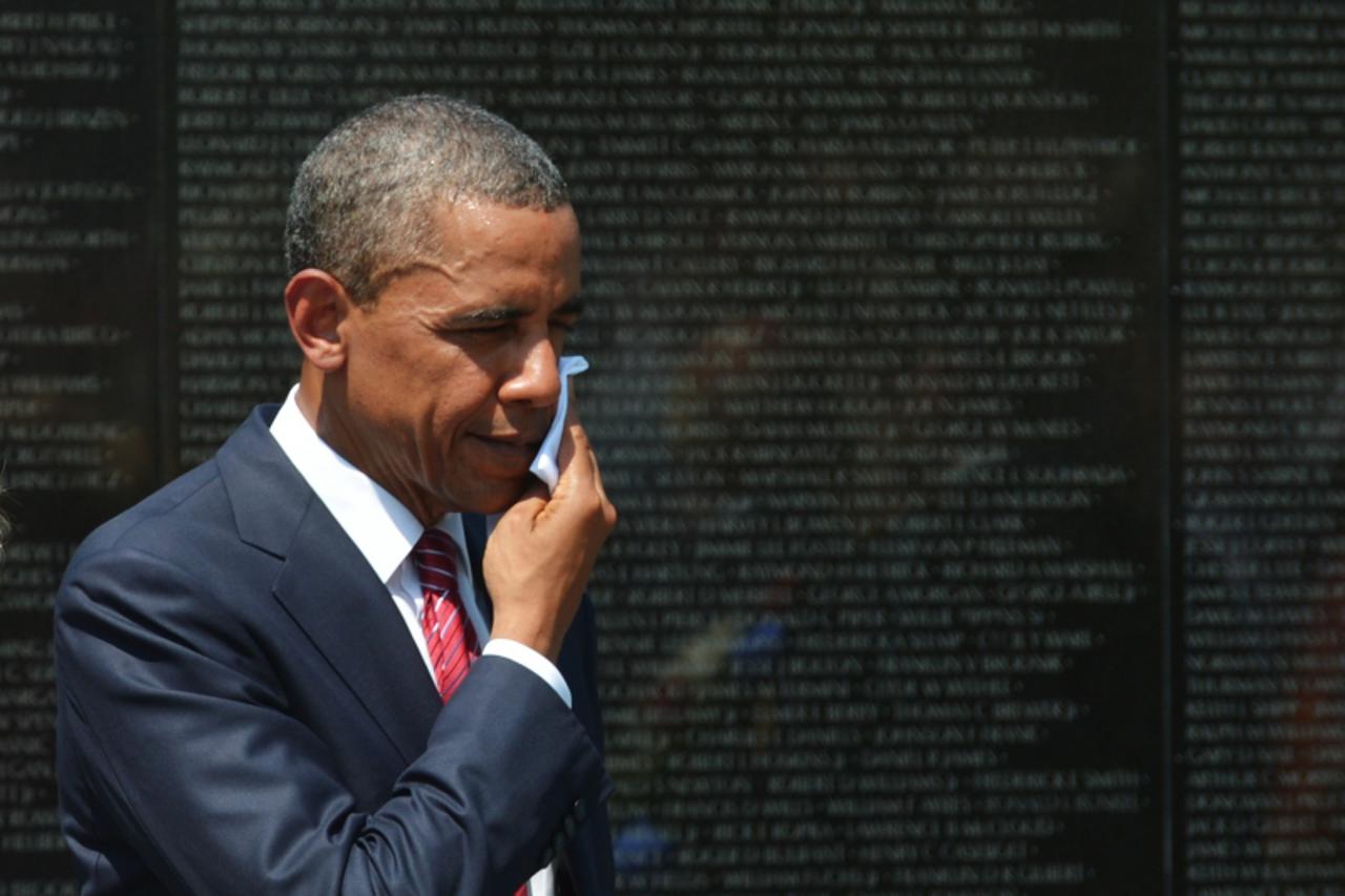 'US President Barack Obama wipes his brow during a ceremony May 28, 2012 at the Vietnam War Memorial in Washington, DC. The Memorial Day event also marks the 50th anniversary of the start of the Vietn