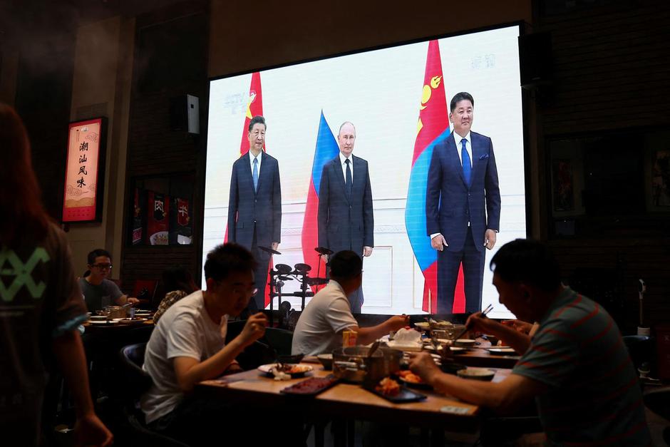 A giant screen broadcasting footage of Chinese President Xi Jinping attending a meeting with Russian President Vladimir Putin at a restaurant in Beijing