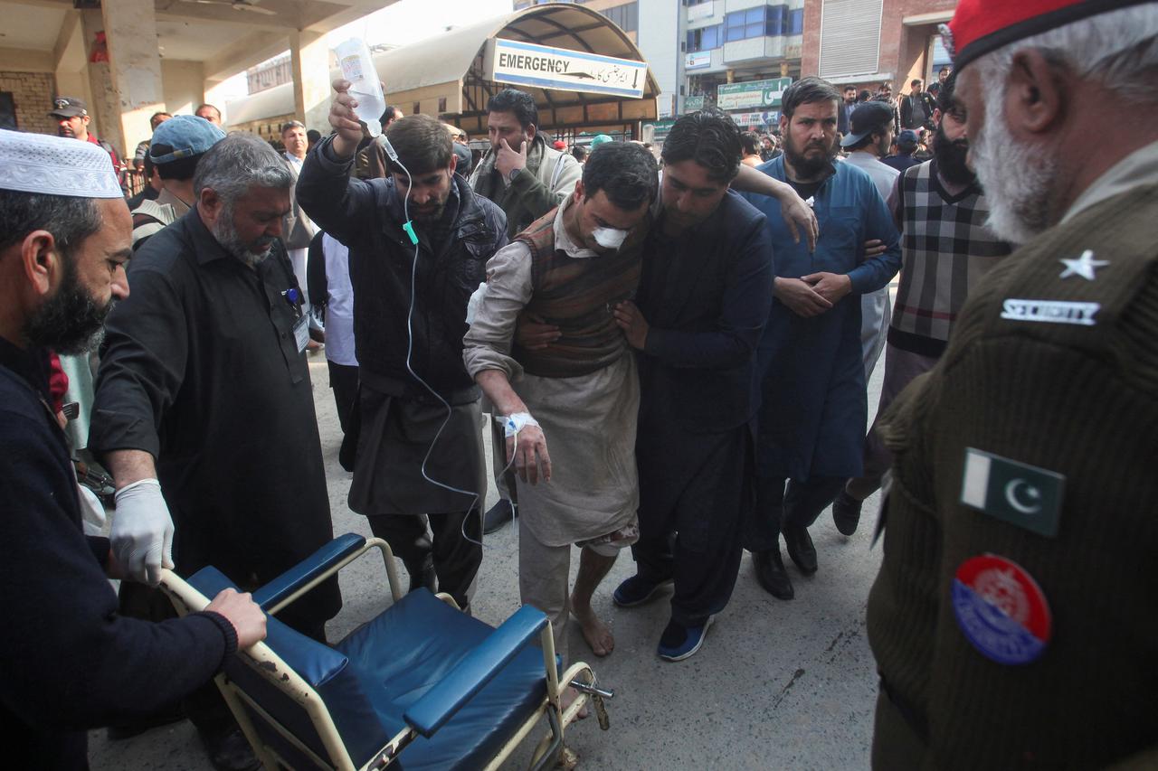 Men move an injured victim, after a suicide blast in a mosque, at hospital premises in Peshawar