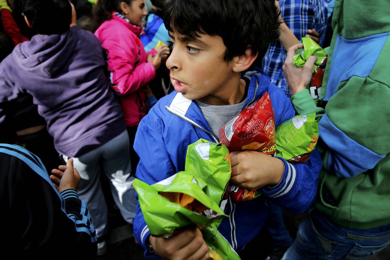 A migrant boy holds snacks during a giveaway by Turkish volunteers living in Berlin outside the Berlin Office of Health and Social Affairs (LaGeSo) as migrants wait for their registration in Berlin, Germany September 21, 2015.  REUTERS/Fabrizio Bensch TPX