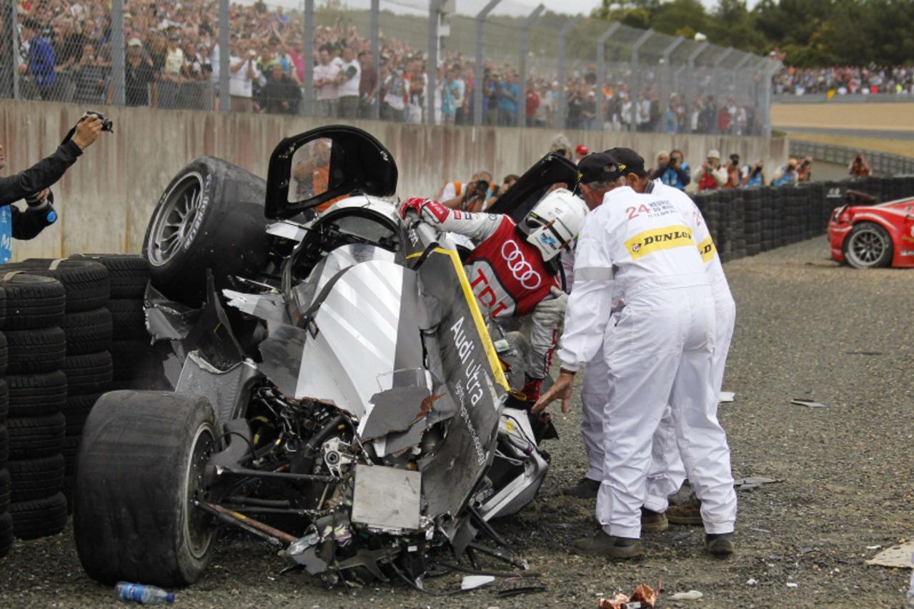 'Safety crew members help Britain\'s Allan Mcnish after he crashed with his Audi R18 TDI during the Le Mans 24-hour sportscar race in Le Mans, central France June 11, 2011. The Audi R18 TDI number 3 w