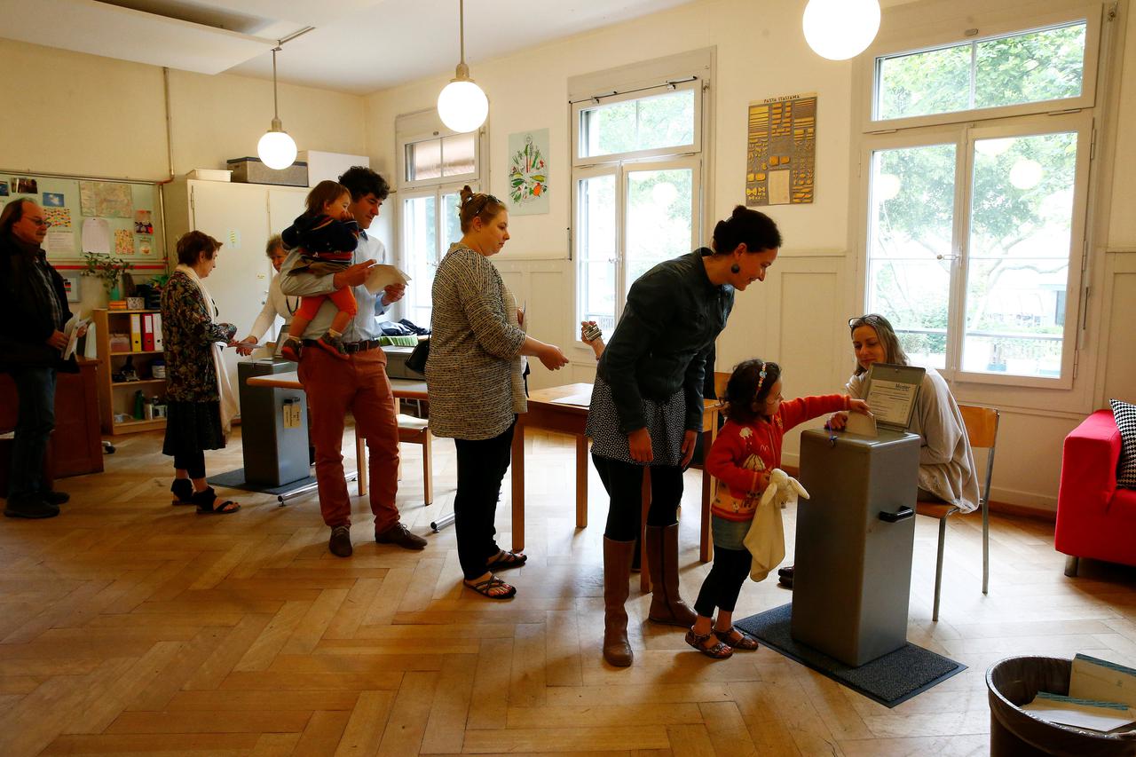 People cast their ballots during a vote on whether to give every adult citizen a basic guaranteed monthly income of 2,500 Swiss francs ($2,560), in a school in Bern, Switzerland, June 5, 2016. REUTERS/Ruben Sprich     TPX IMAGES OF THE DAY     