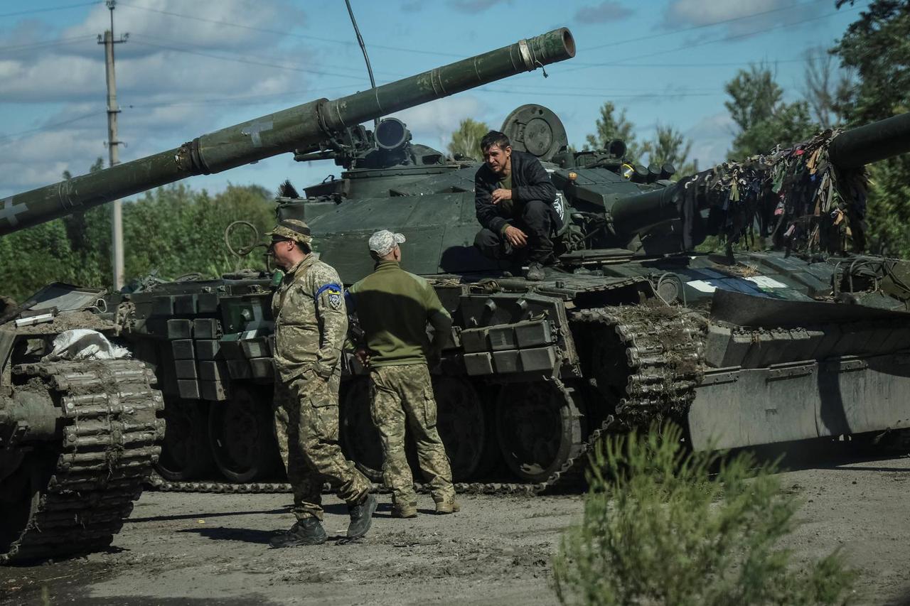 Ukrainian servicemen stand near tanks near the town of Izium