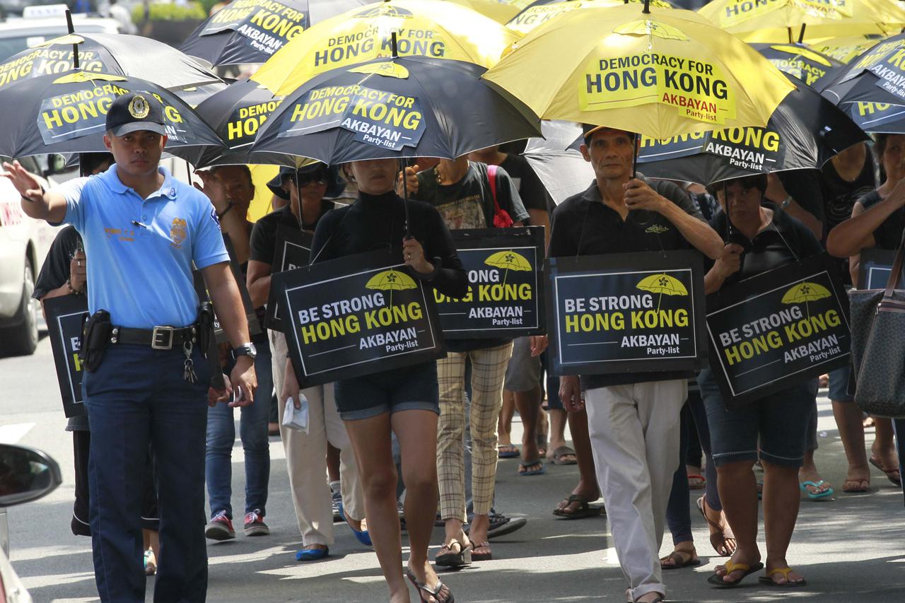 A policeman conducts traffic to give way to activists marching towards the Chinese Consular office in Makati city, metro Manila October 2, 2014. Dozens of Filipino activists demonstrated in Manila on Thursday in support of Hong Kong protesters demanding d