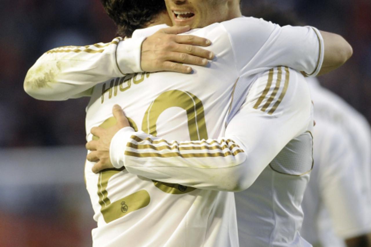 'Real Madrid\'s Argentinian forward Gonzalo Higuain (L) is congratulated by Portuguese forward Cristiano Ronaldo (R) after scoring his team\'s third goal during the Spanish football match CA Osasuna v