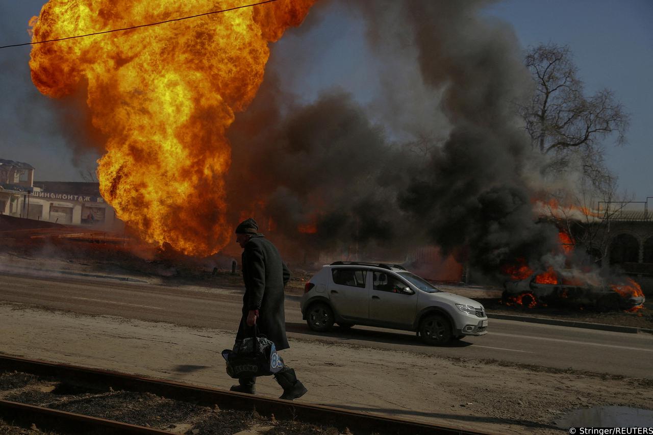 FILE PHOTO: A man walks past a fire after a shelling, as Russia's attack on Ukraine continues