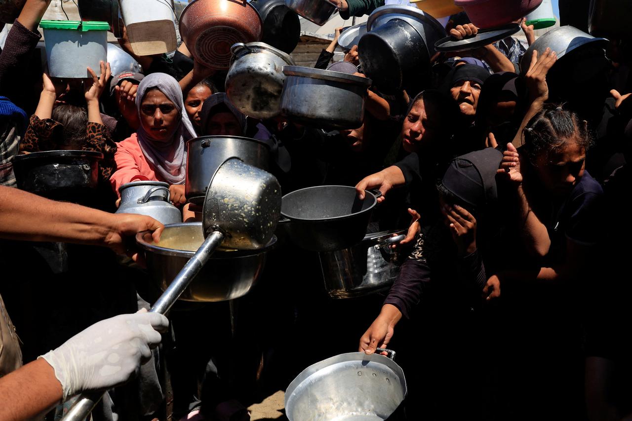 Palestinians wait to receive food from a charity kitchen, amid a hunger crisis, in Khan Younis