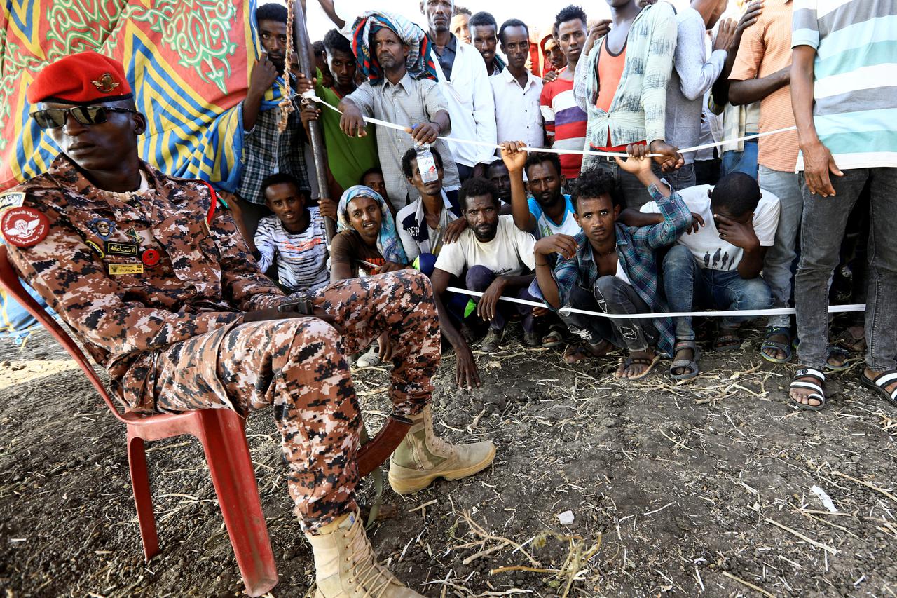 Sudanese military officer keeps guard as Ethiopians who fled war in Tigray region, gather to receive relief supplies from the World Food Programme at the Fashaga camp on the Sudan-Ethiopia border in Al-Qadarif state