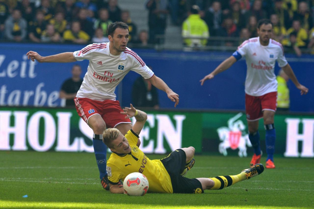 'Hamburg\'s croatian midfielder Milan Badelj (L) and Dortmund\'s Dortmund\'s striker Marco Reus (C) vie for the ball during the German Bundesliga football match Hamburg vs Dortmund on September 22, 20