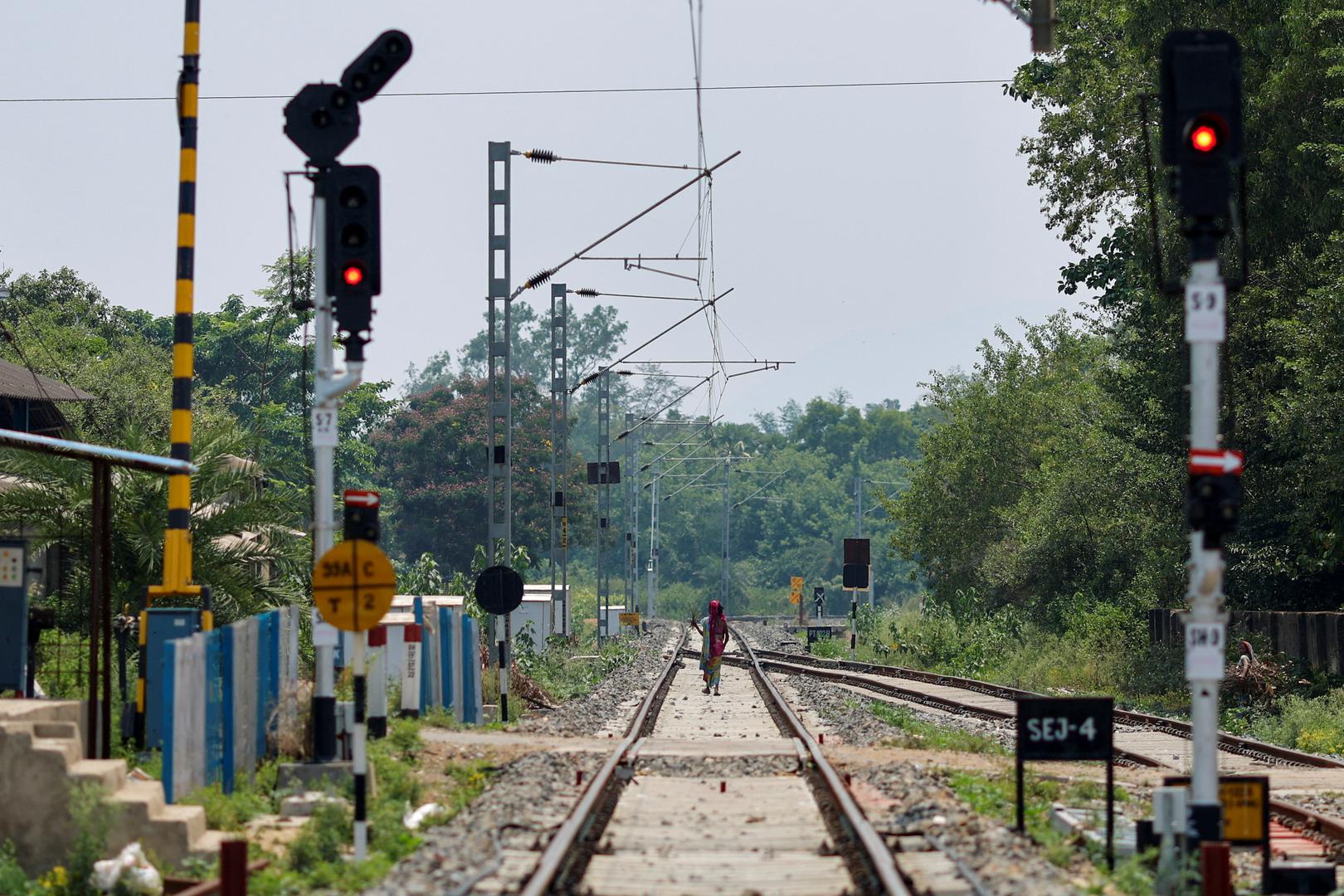 Railway signals are pictured at a crossing as a woman walks on the tracks at the site of a train collision following the accident in Balasore district in the eastern state of Odisha, India, June 4, 2023. REUTERS/Adnan Abidi Photo: ADNAN ABIDI/REUTERS