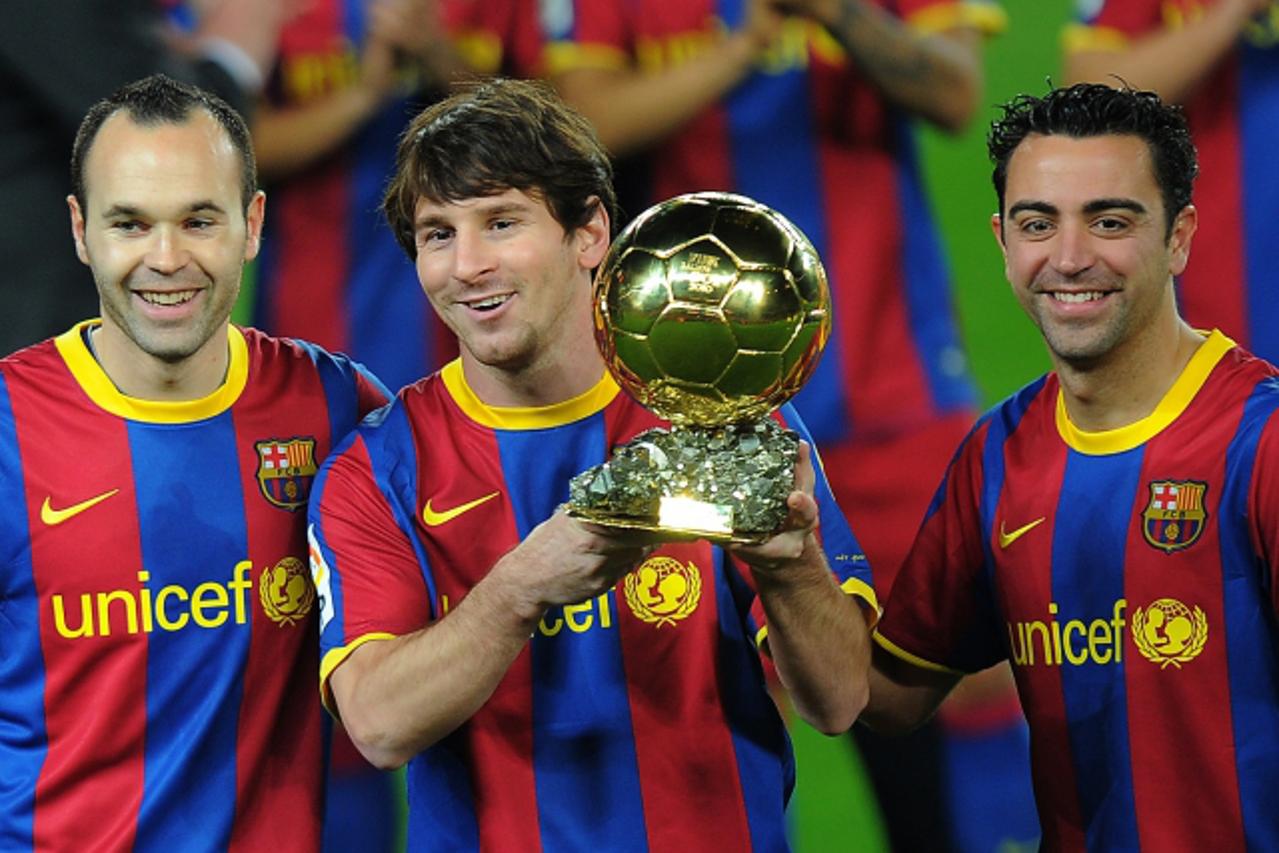 'Barcelona\'s Argentinian forward Lionel Messi (C), flanked with Barcelona\'s midfielder Xavi Hernandez (R) and Barcelona\'s midfielder Andres Iniesta (L), poses with the 2010 Ballon d\'Or trophy (Gol
