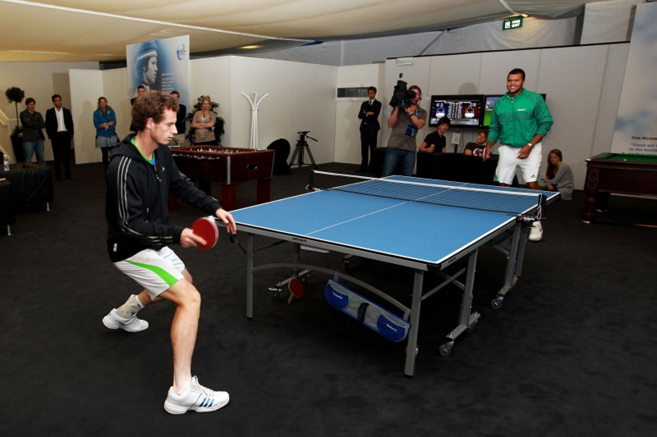 'Andy Murray of Great Britain (L) and Jo-Wilfred Tsonga of France play table tennis in the players lounge due to the postponement of the final of the ATP tournament at Queen\'s tennis club, in London,