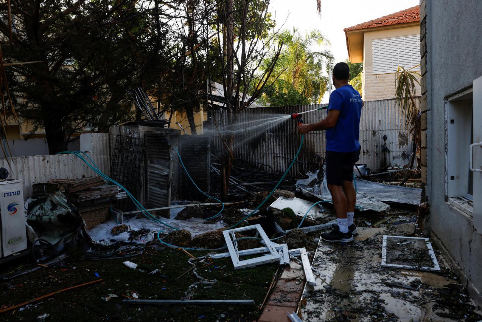 A man sprays down burned objects, in the aftermath of rocket barrages that were launched from Gaza, in Ashkelon, Israel October 7, 2023. REUTERS/Amir Cohen Photo: AMIR COHEN/REUTERS