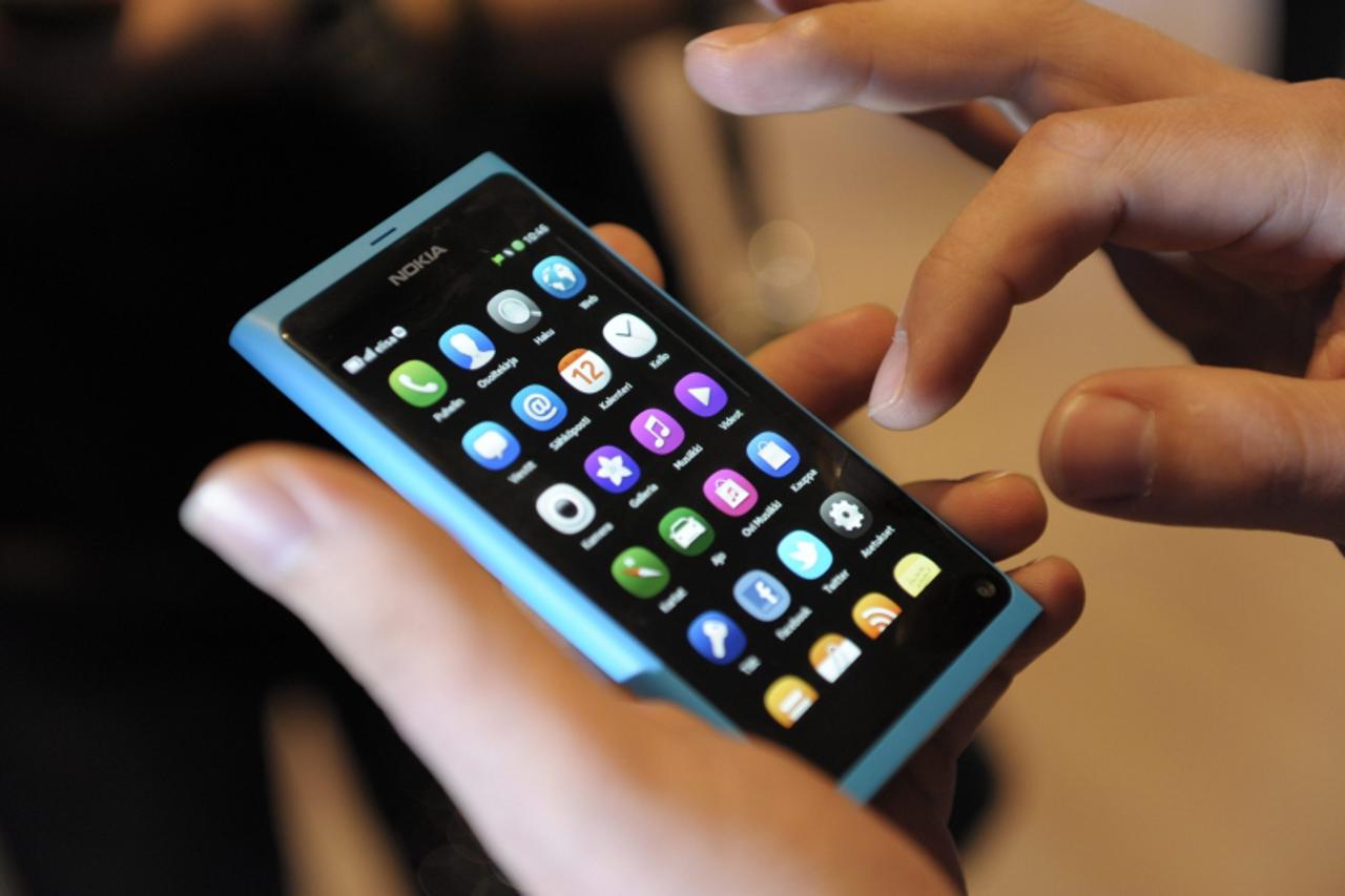 \'A staff member displays a Nokia N9 smartphone at a news conference in Espoo, June 21, 2011. REUTERS/Heikki Saukkomaa/Lehtikuva (FINLAND - Tags: BUSINESS SCI TECH) THIS IMAGE HAS BEEN SUPPLIED BY A T