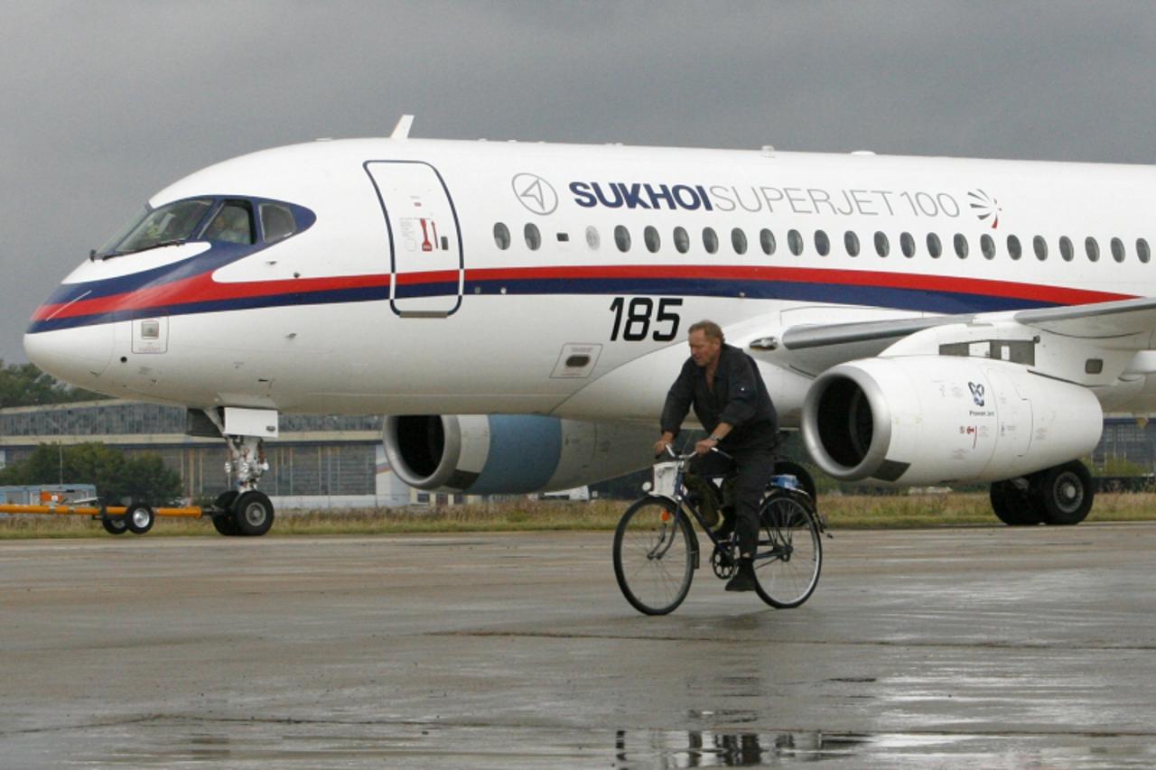 'A cyclist rides past a Sukhoi Superjet 100, an airplane-participant of the MAKS-2009 international air show, in Zhukovsky, outside Moscow, August 14, 2009. The annual air show, a marketplace for airl