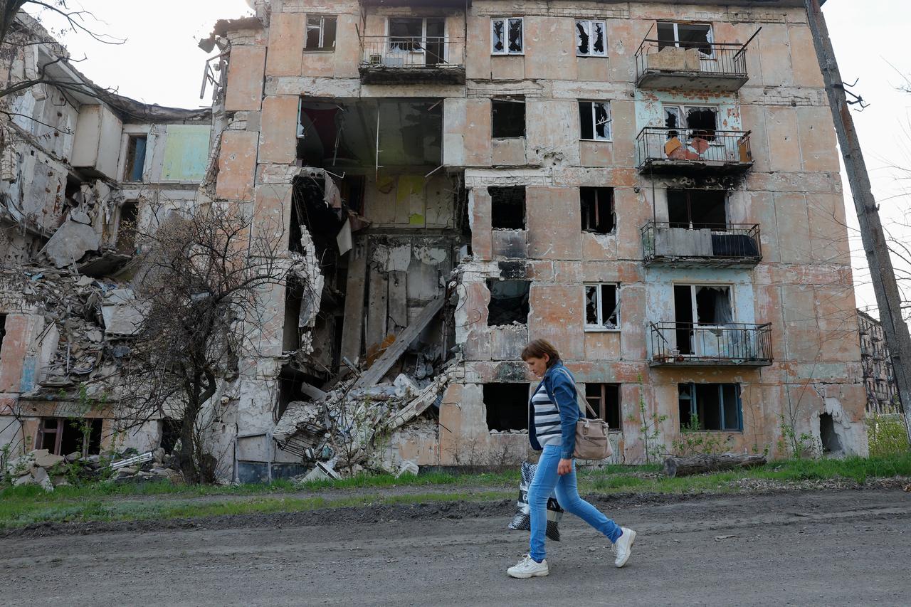 A woman walks past a destroyed building in Toshkivka amid Russia-Ukraine conflict