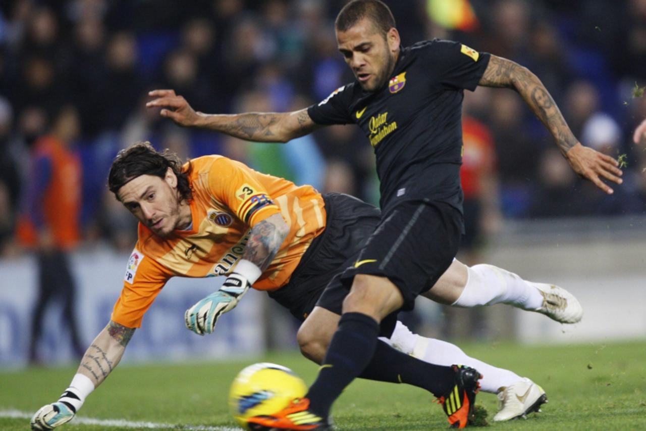 'Espanyol\'s goalkeeper Cristian Alvarez (L) tries to block a ball against Barcelona\'s Dani Alves during their Spanish First division soccer match at Cornella-El Prat stadium, near Barcelona, January