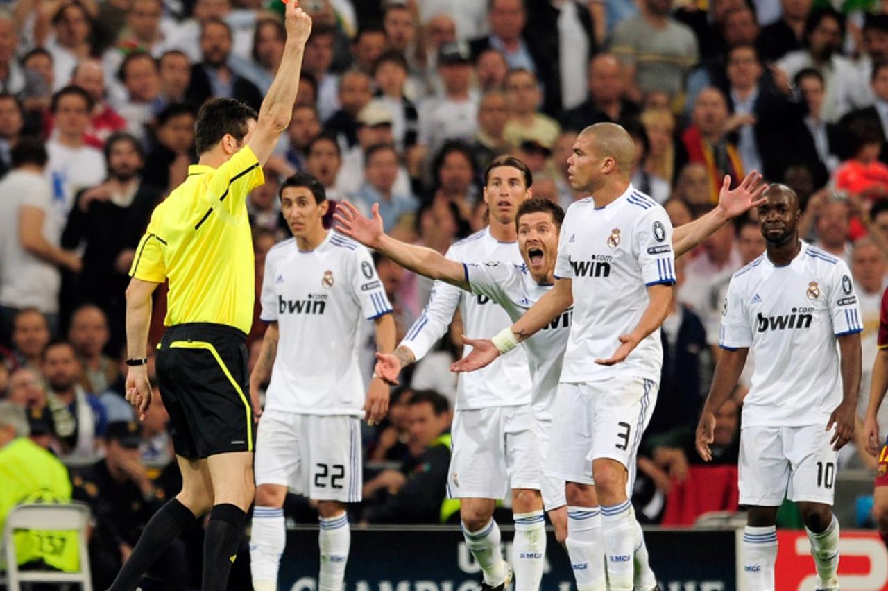 'Real Madrid\'s Portuguese defender Pepe (R) receives a red card from referee Wolfgang Stark during the Champions League semi-final first leg football match between Real Madrid and Barcelona at the Sa