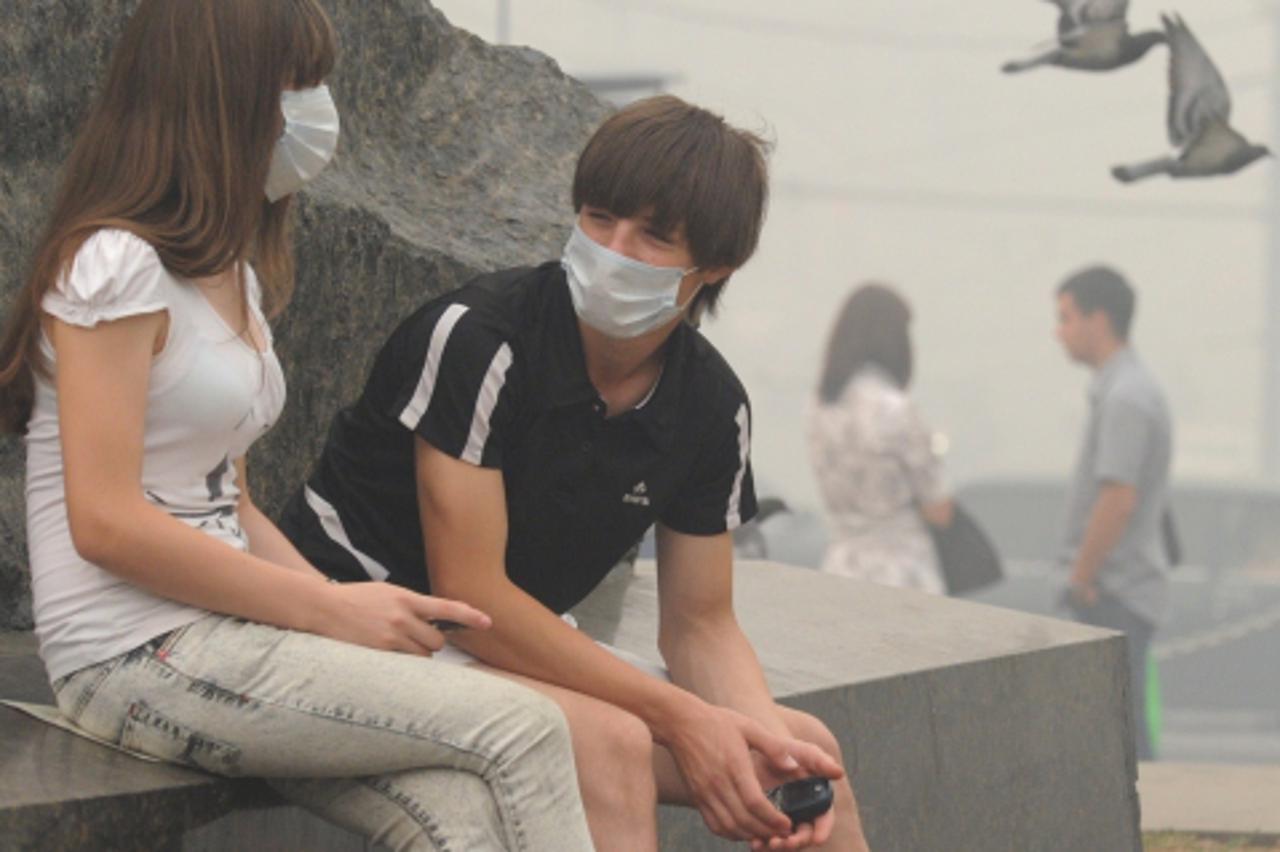 'A Russian couple has a conversation while wearing facemasks to protect themselves from forest fire smog in central Moscow on August 6, 2010. Smog from wildfires in the countryside cloaked Moscow, wit