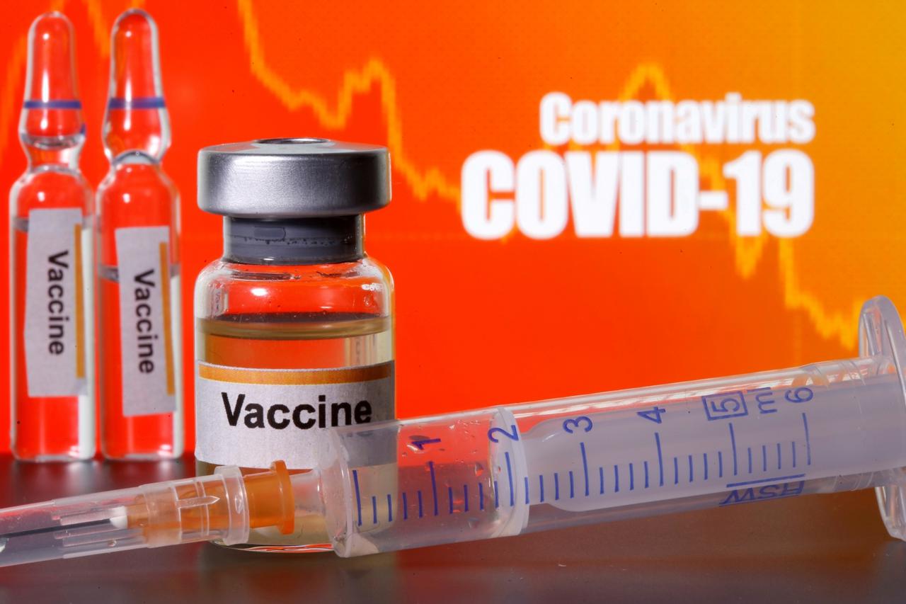 FILE PHOTO: Small bottles labeled with "Vaccine" stickers stand near a medical syringe in front of displayed "Coronavirus COVID-19" words in this illustration