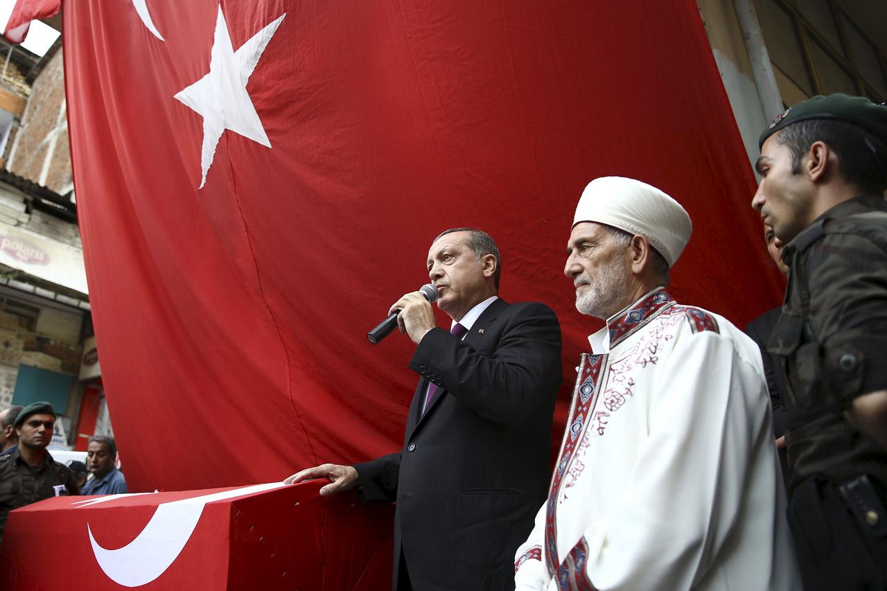 Turkish President Tayyip Erdogan (3rd R) speaks next to the flag-draped coffin of slain police officer Ahmet Camur, who was killed during clashes with PKK militants, during a funeral ceremony in Trabzon, Turkey, August 16, 2015. As efforts to form a new g