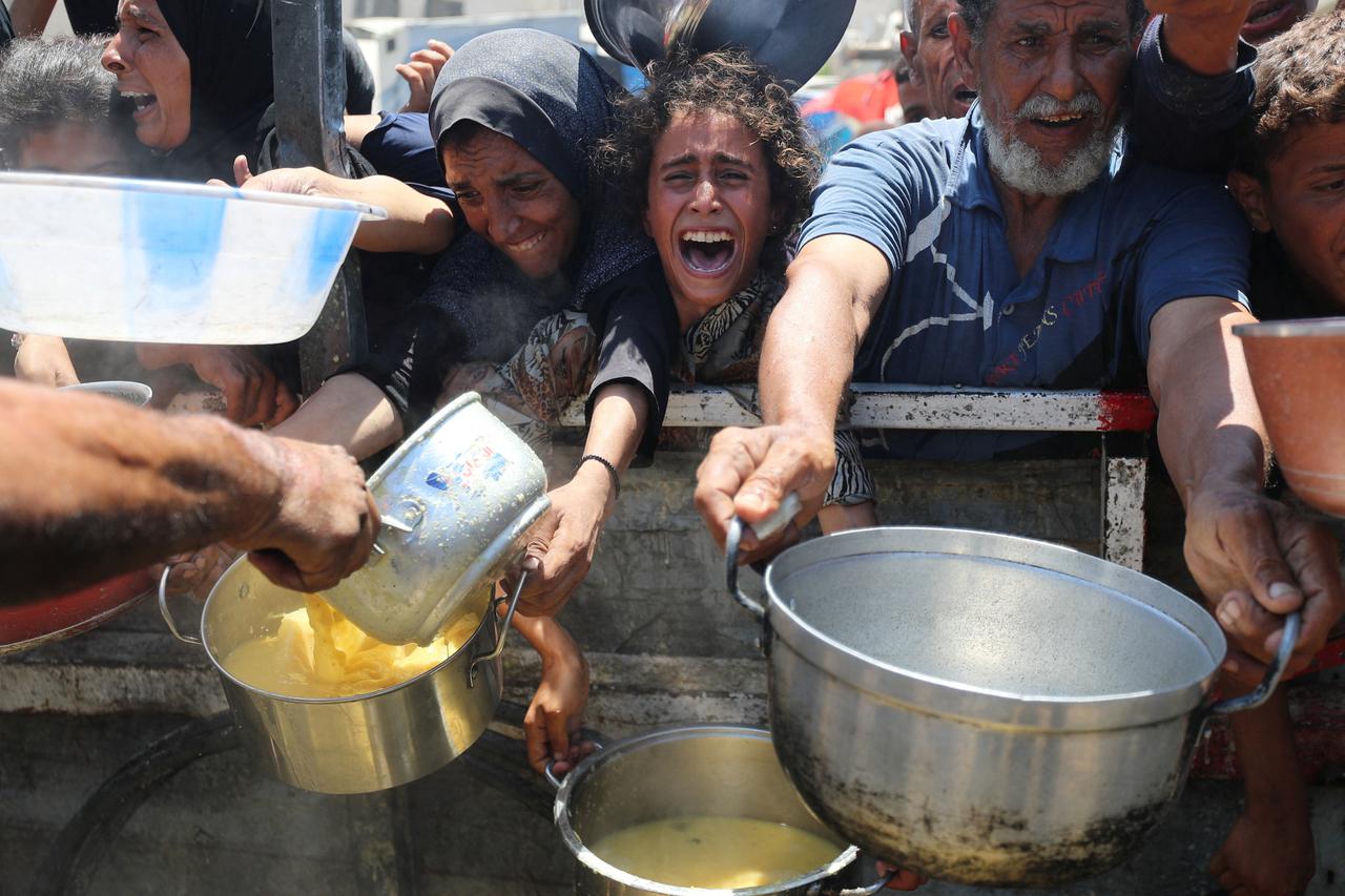 Palestinians wait to receive food from a charity kitchen, amid a hunger crisis, in Gaza City