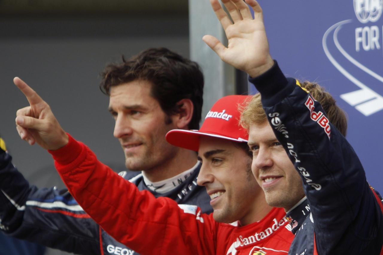 'Ferrari Formula One driver Fernando Alonso (C) of Spain celebrates after winning the pole position ahead of Red Bull Formula One driver Sebastian Vettel of Germany (R) and Red Bull Formula One driver