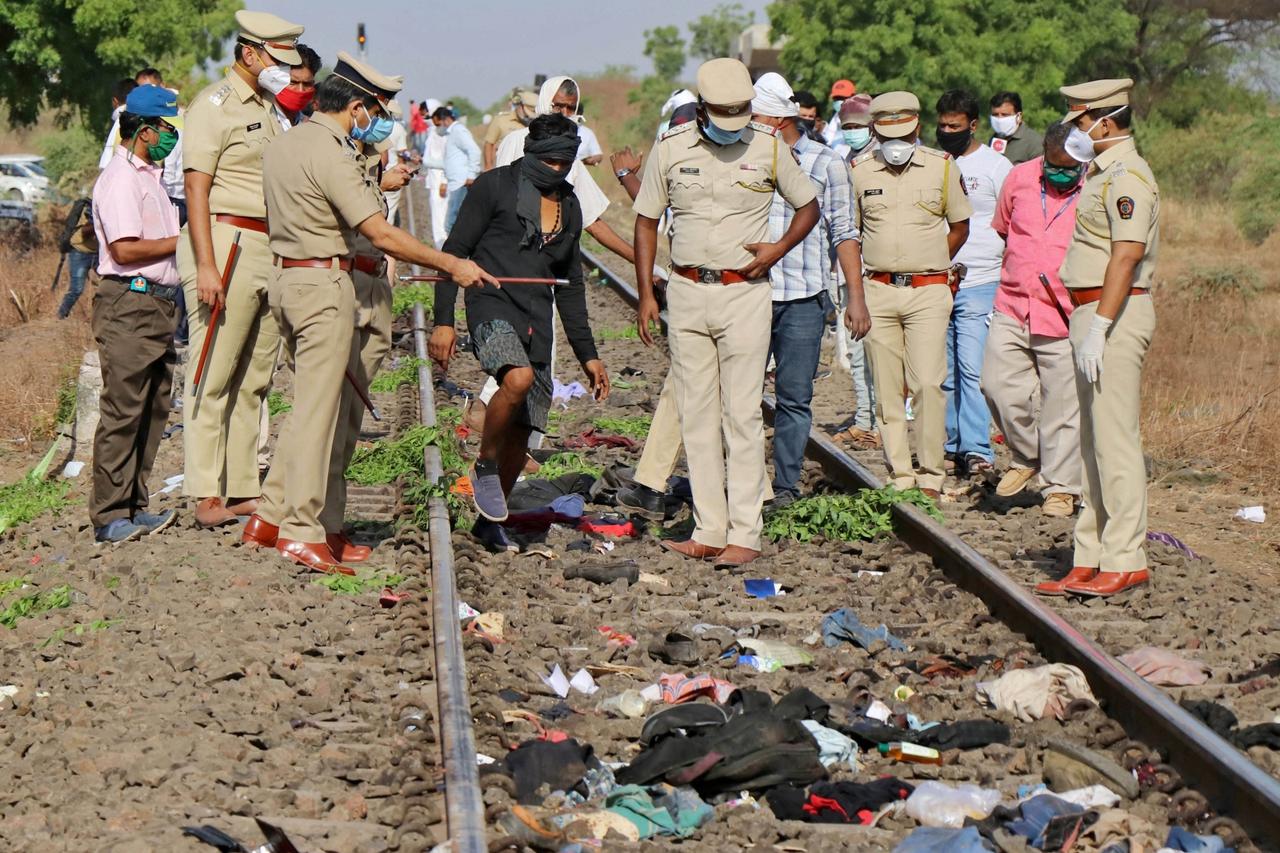Police officers examine the railway track after a train ran over migrant workers sleeping on the track in Aurangabad district