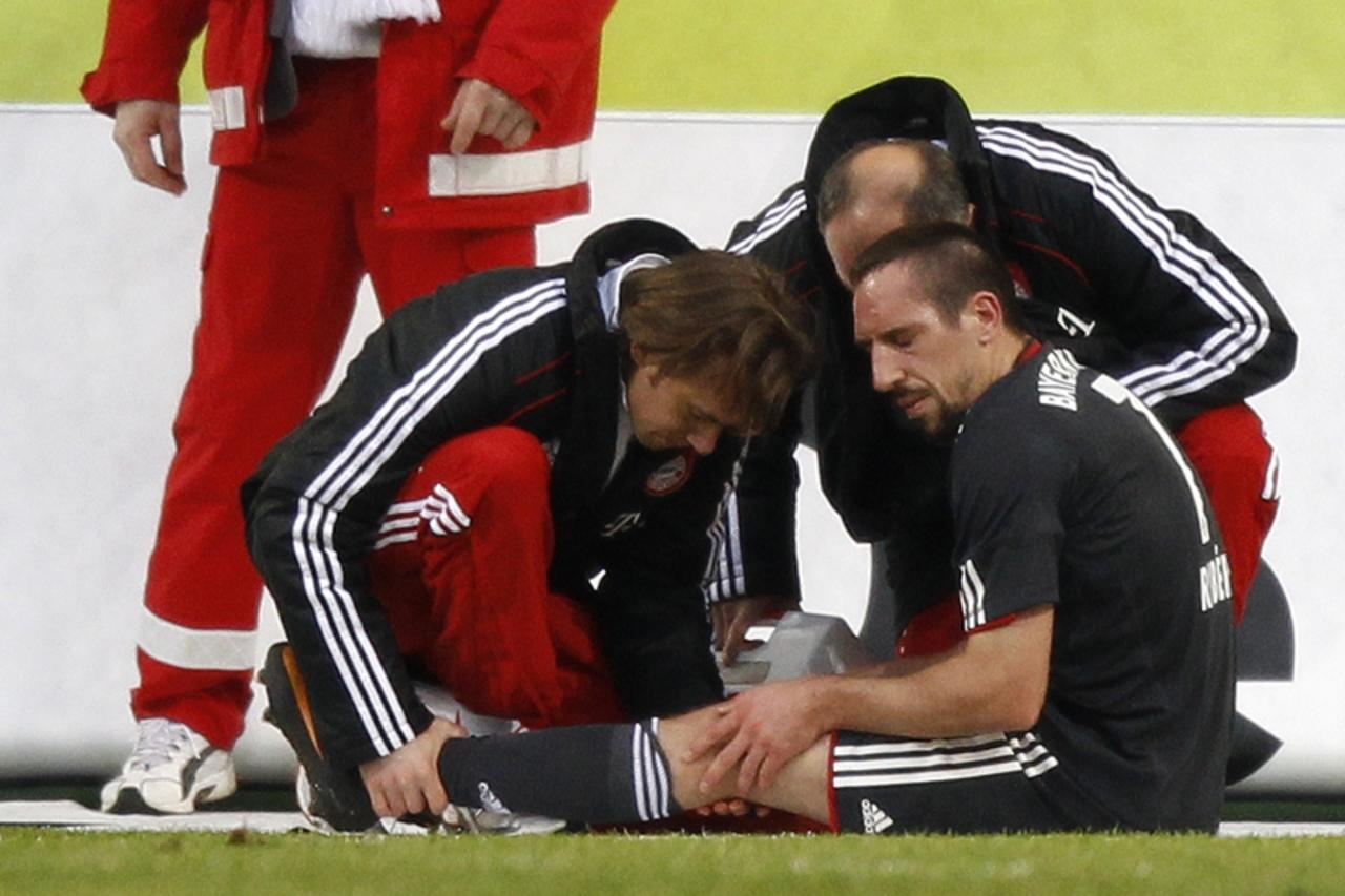 \'Bayern Munich\'s Franck Ribery (R) is checked by team officials following a tackle during their German first division Bundesliga soccer match against VfL Wolfsburg in Wolfsburg January 15, 2011. REU
