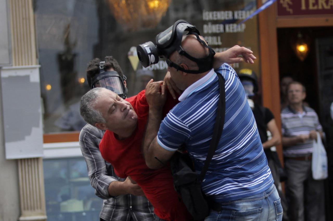 'Plain clothes policemen detain an anti-government protester at Taksim square in central Istanbul June 16, 2013. Riot police fired occasional bursts of teargas in Istanbul on Sunday after a night of u