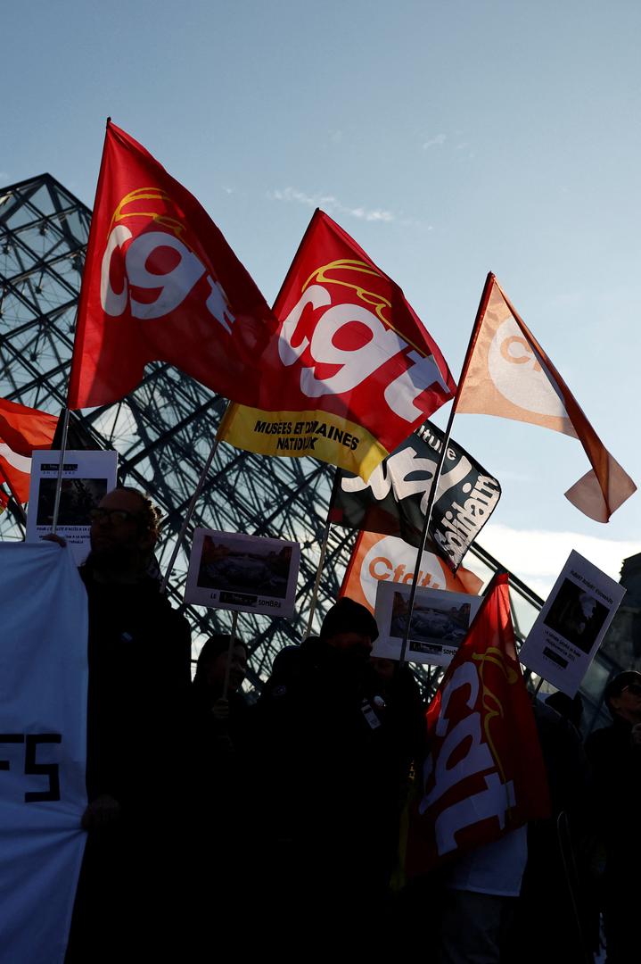 Louvre museum employees on strike hold CGT, CFDT Culture and Sud Solidaires labour unions flags near the glass Pyramid of the closed Louvre museum to protest their working conditions, the state of the museum's buildings and staffing issues, two months after a spectacular heist which saw thieves make off with jewels in broad daylight, in Paris, France, December 15, 2025. REUTERS/Benoit Tessier Photo: BENOIT TESSIER/REUTERS