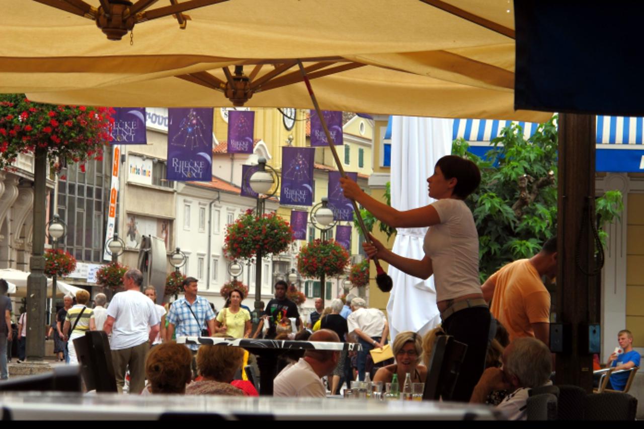 '18.07.2011. Rijeka - Konobarica skida kisnicu sa tende na terasi na Korzu. Photo: Goran Kovacic/PIXSELL'