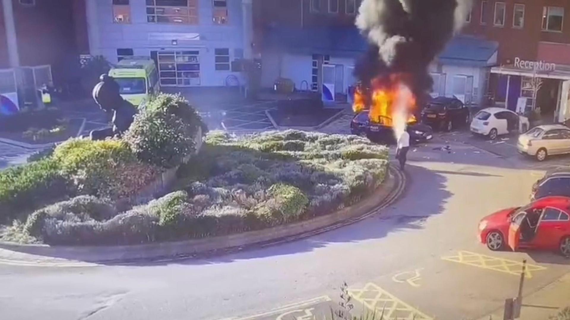 A surveillance camera footage shows a man extinguishing a burning taxi following an explosion, outside Liverpool Women's hospital in Liverpool, Britain November 14, 2021 in this still image obtained from a video on November 15, 2021. CCTV/via REUTERS THIS IMAGE HAS BEEN SUPPLIED BY A THIRD PARTY. NO RESALES. NO ARCHIVES.