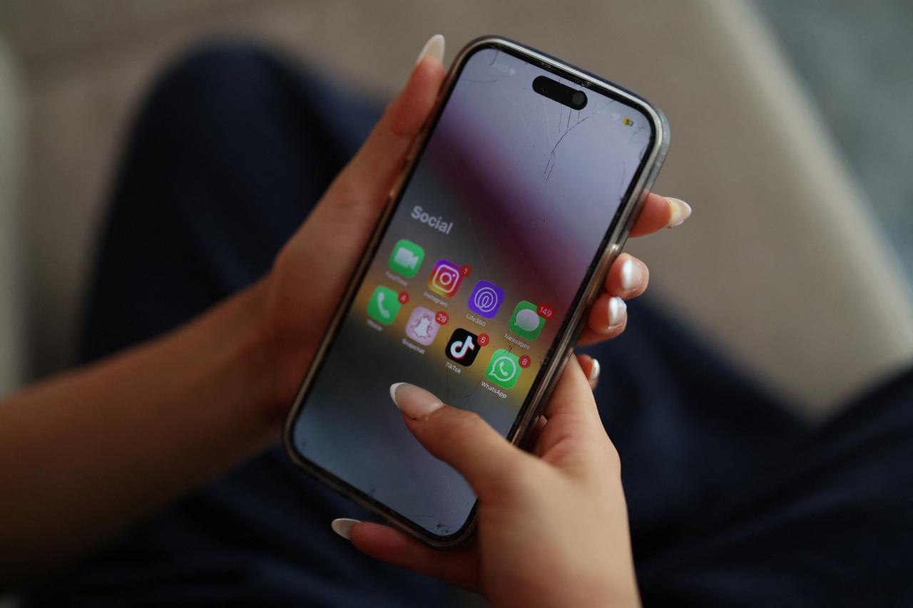 Claire Ni, 14, poses holding a mobile phone as a law banning social media for users under 16 in Australia takes effect, in Sydney