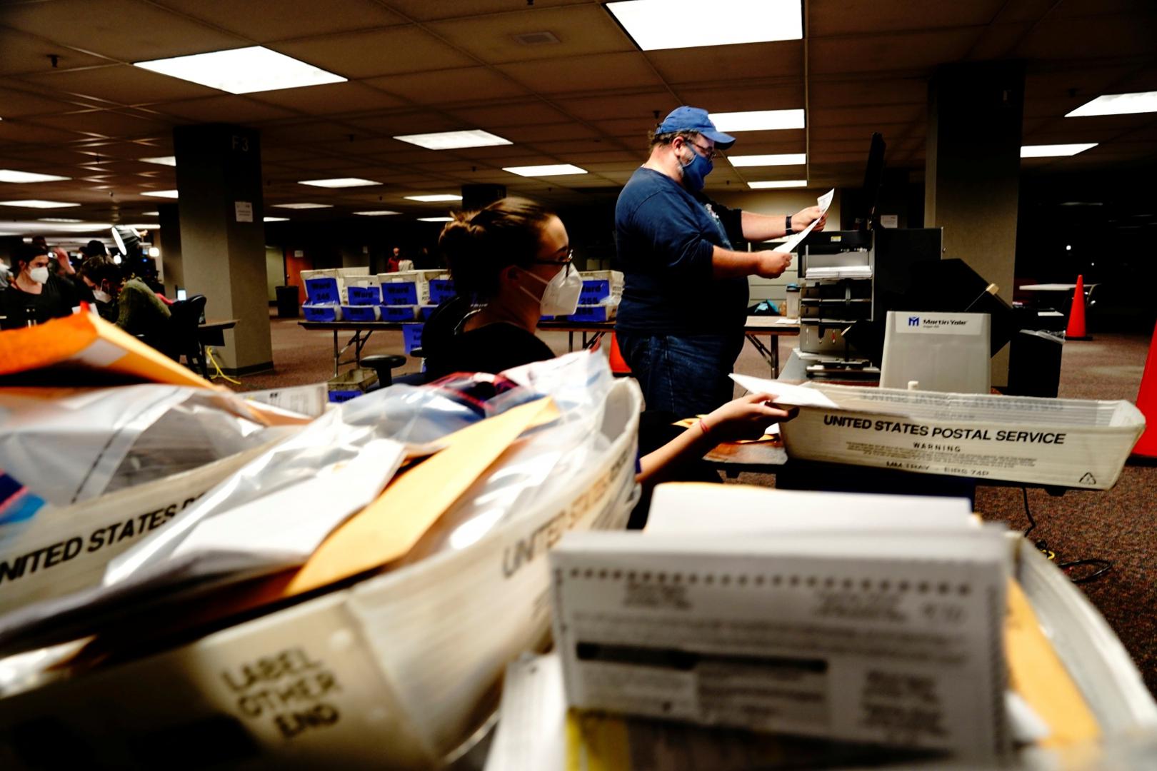 Counting absentee ballots at Milwaukee Central Count Poll workers Erin Keleske and Brett Rohlwing use a tabulator machine to process absentee ballots the night of Election Day at Milwaukee Central Count in Milwaukee, Wisconsin, U.S., November 3, 2020. REUTERS/Bing Guan BING GUAN