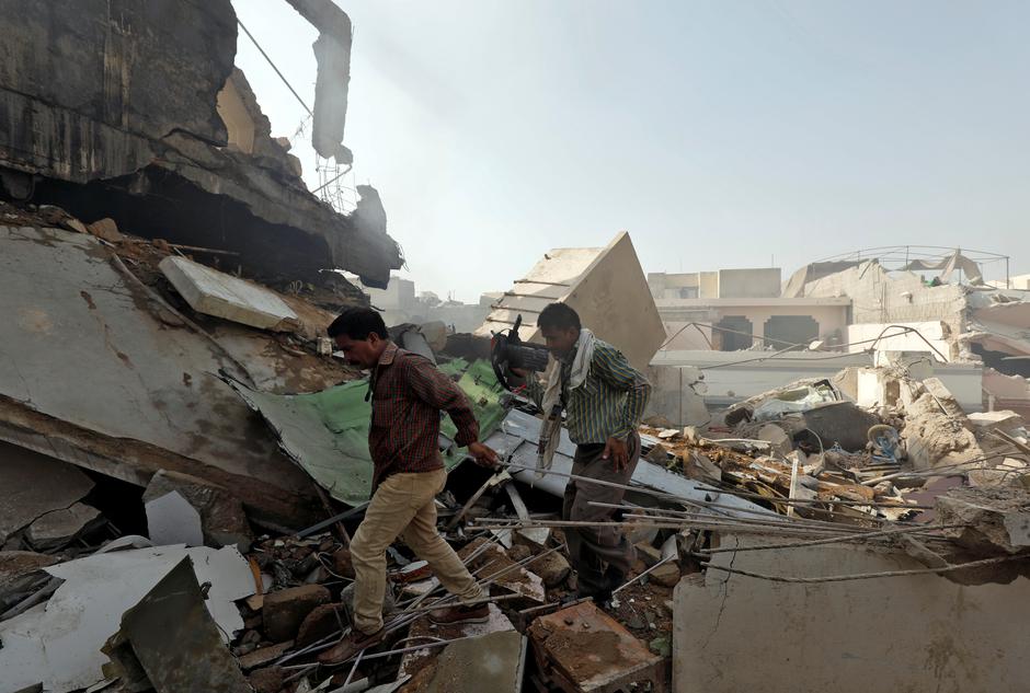 Men walk on the debris at the site of a passenger plane crash in a residential area near an airport in Karachi