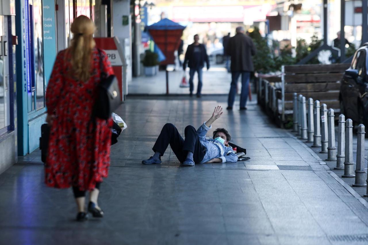Muškarac leži na podu pretvarajući se da ima koronavirus te prolaznike traži novac