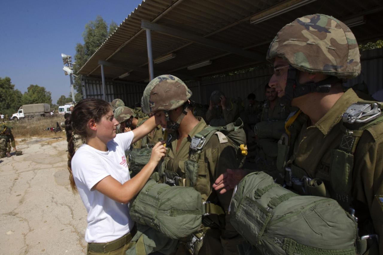 'A parachuting instructor inspects the gear worn by soldiers before a jump, during a parachuting course at Tel Nof air force base near Tel Aviv September 18, 2011. Soldiers jump from a plane several t