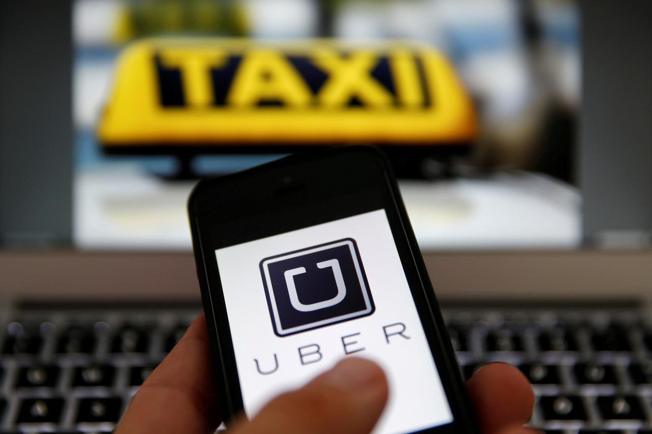 An illustration picture shows the logo of car-sharing service app Uber on a smartphone next to the picture of an official German taxi sign September 15, 2014.    REUTERS/Kai Pfaffenbach/Illustration/File Photo