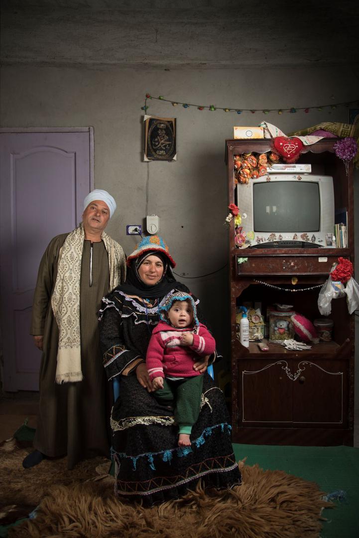 Beduinski muž stoji pokraj svoje supruge, dok se njihova unuka odmara u njezinu krilu