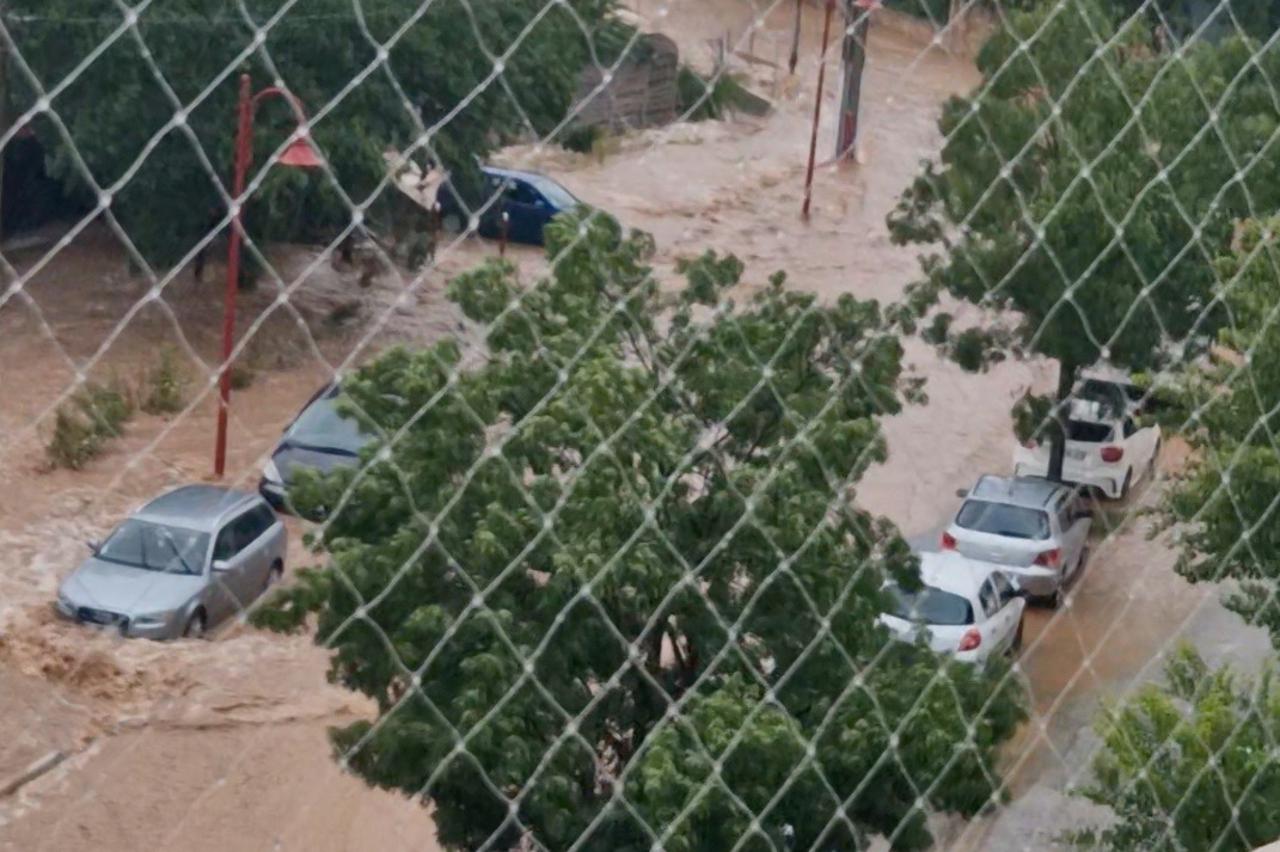 Cars are seen parked amid flood waters running down a street in Vidauban