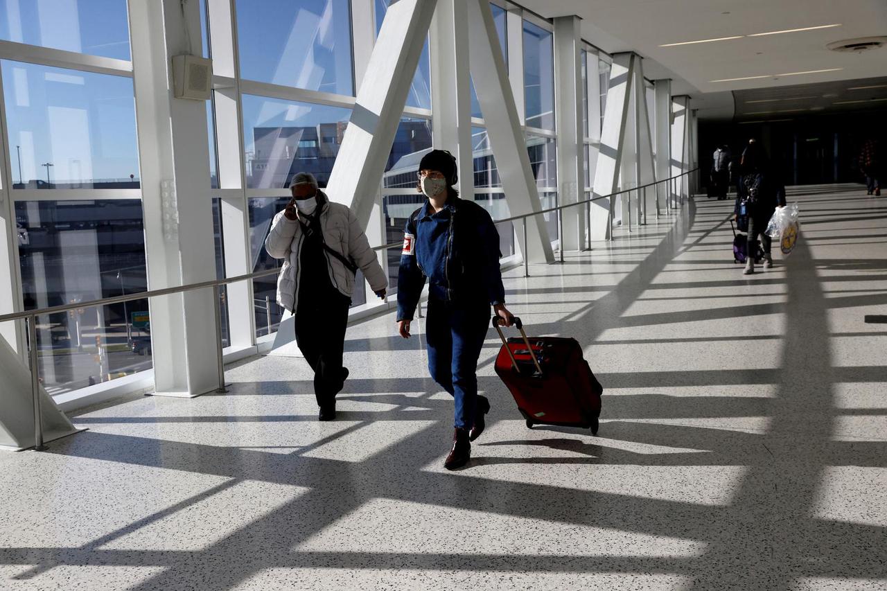 FILE PHOTO: Air travellers wearing a protective face masks, amid the coronavirus disease (COVID-19) pandemic, at JFK International airport in New York